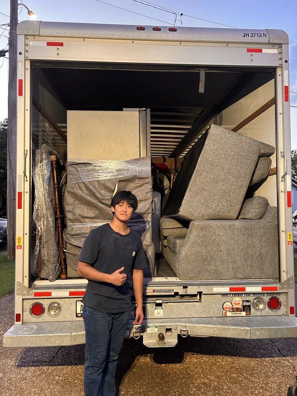 SmartStack Moving crew member at back of loaded moving truck with sofa and wrapped furniture at dusk